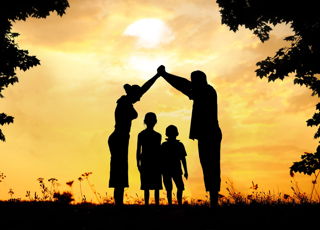 Silhouette of a family, the parents holding hands above the heads of two children to form a bridge.