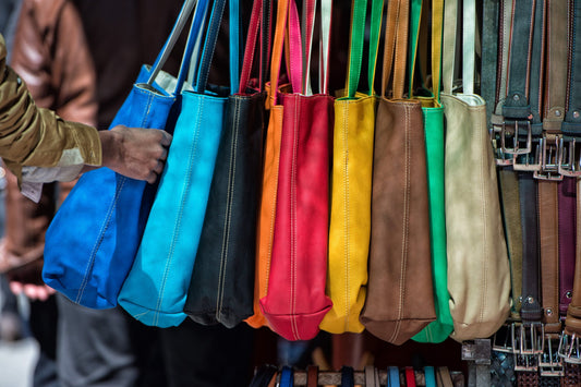 A variety of handbags in many different colors on display at a store.