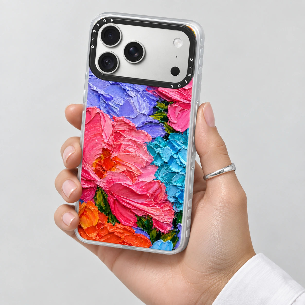 Bloom Riot's vivid pink, lilac and blue floral phone case held in one hand