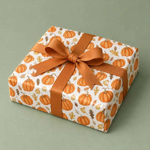 Autumn pumpkin wrapping paper with a copper grosgrain bow on a sage studio background